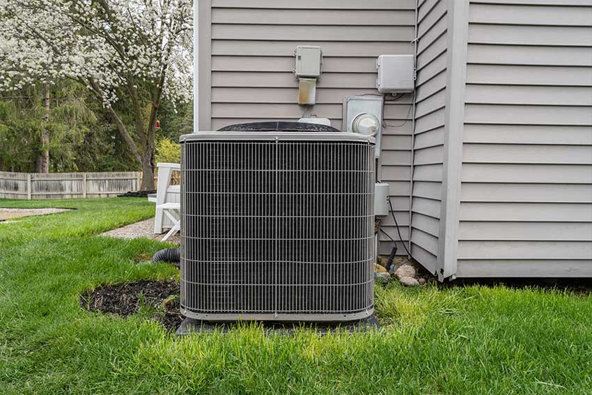 Central AC unit installed on a concrete pad outside a house